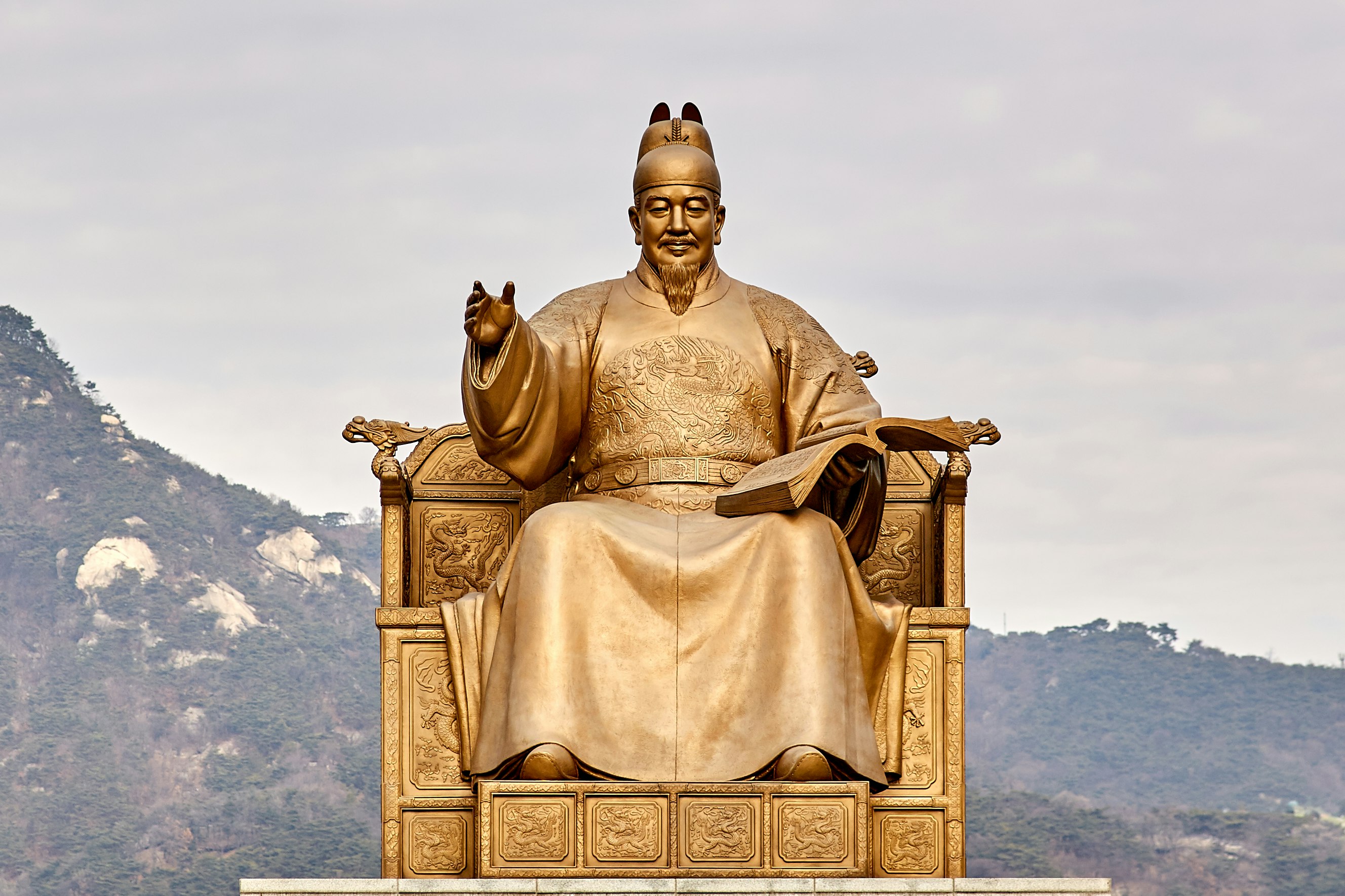 gold statue of man sitting on throne